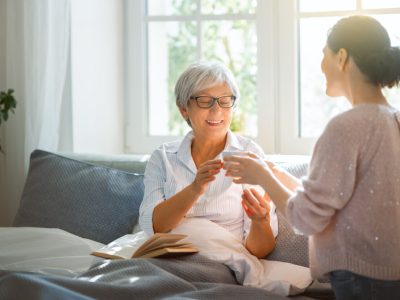 beautiful-senior-mother-adult-daughter-are-talking-smiling-while-sitting-bed-home-1170x828